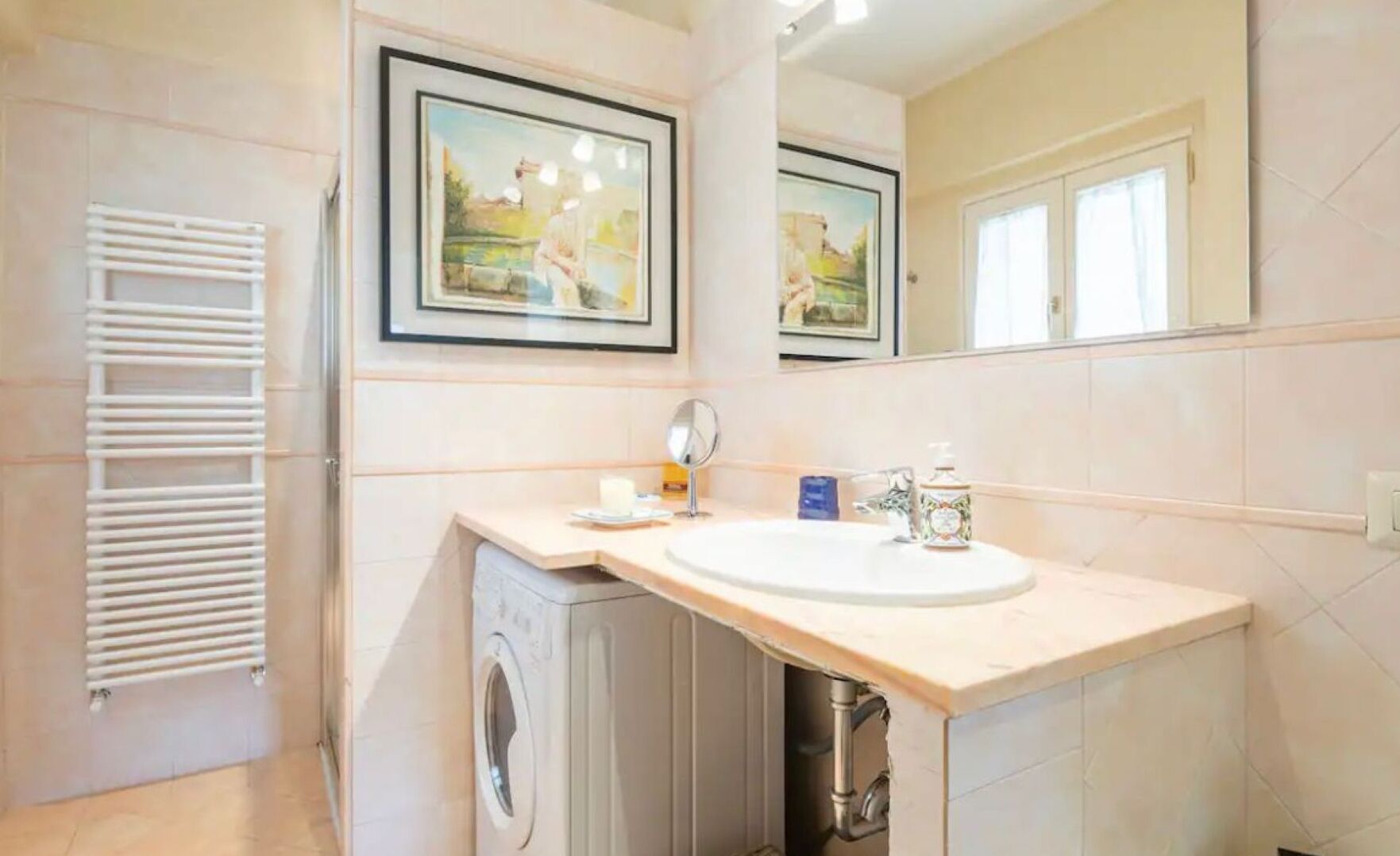 Une salle de bain avec un lavabo, un miroir et un tableau encadré au mur.