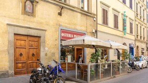 A street view with a building housing an Osteria Pasta restaurant, a glass-enclosed outdoor seating area, and parked motorcycles. - Lusso e Charme
Wonderful apartment in the city center of Florence! (Firenze)