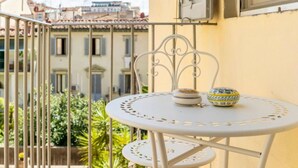 A balcony with a white metal table and chairs, a small decorative bowl, and a window with shutters. - Lusso e Charme
Wonderful apartment in the city center of Florence! (Firenze)