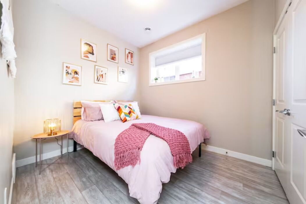 A bedroom with a bed, bedside tables, a window, and wall art.