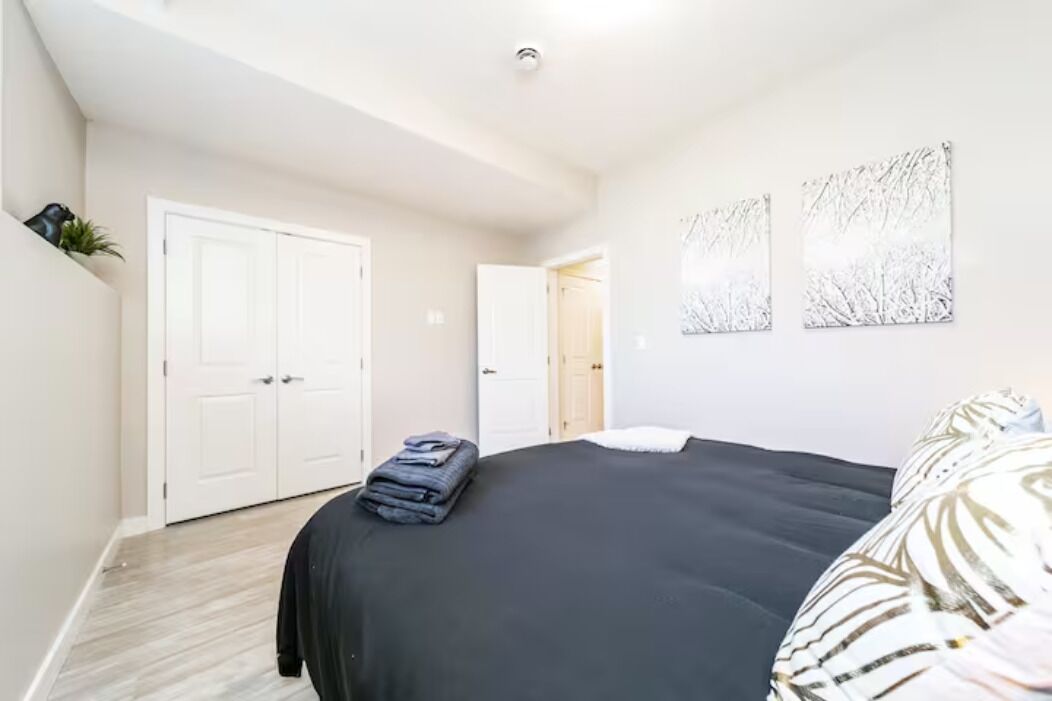 A bedroom with a bed, a wardrobe, and two artwork pieces on the wall.