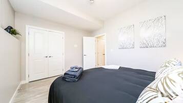 A bedroom with a bed, a wardrobe, and two artwork pieces on the wall.