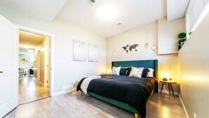 A modern bedroom with a green upholstered bed, a white wardrobe, and a small bedside table with a lamp. - Bright Spacious Suite - King Bed - Long Stays - WiFi
 (Edmonton)