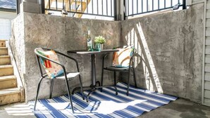 A small, enclosed patio area with two chairs and a table, featuring a concrete wall and a striped rug. - Bright Spacious Suite - King Bed - Long Stays - WiFi
 (Edmonton)