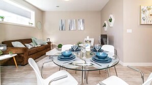 A dining area with a round glass table set for four, surrounded by white chairs. - Bright Spacious Suite - King Bed - Long Stays - WiFi
 (Edmonton)