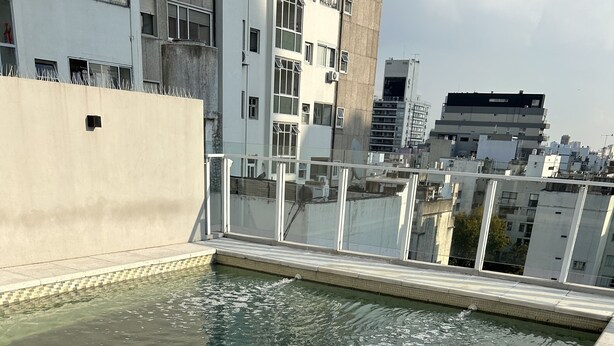 A rooftop swimming pool with clear water, surrounded by a tiled deck and a high wall. - CloudBA Guemes Soho Apartments (Buenos Aires)