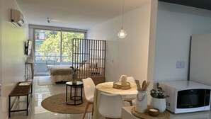 A modern living space with a dining area, a kitchen with a microwave, and a view of the outdoors. - CloudBA Guemes Soho Apartments (Buenos Aires)