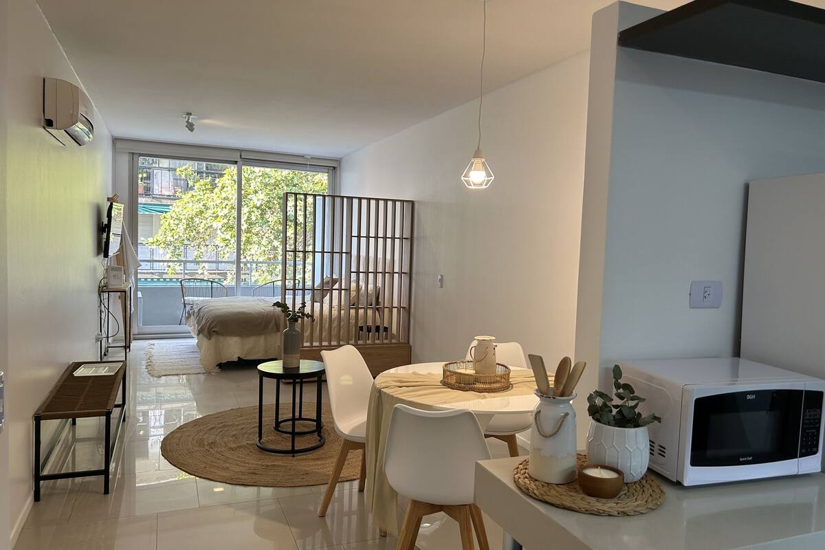 A modern living space with a dining area, a kitchen with a microwave, and a view of the outdoors.