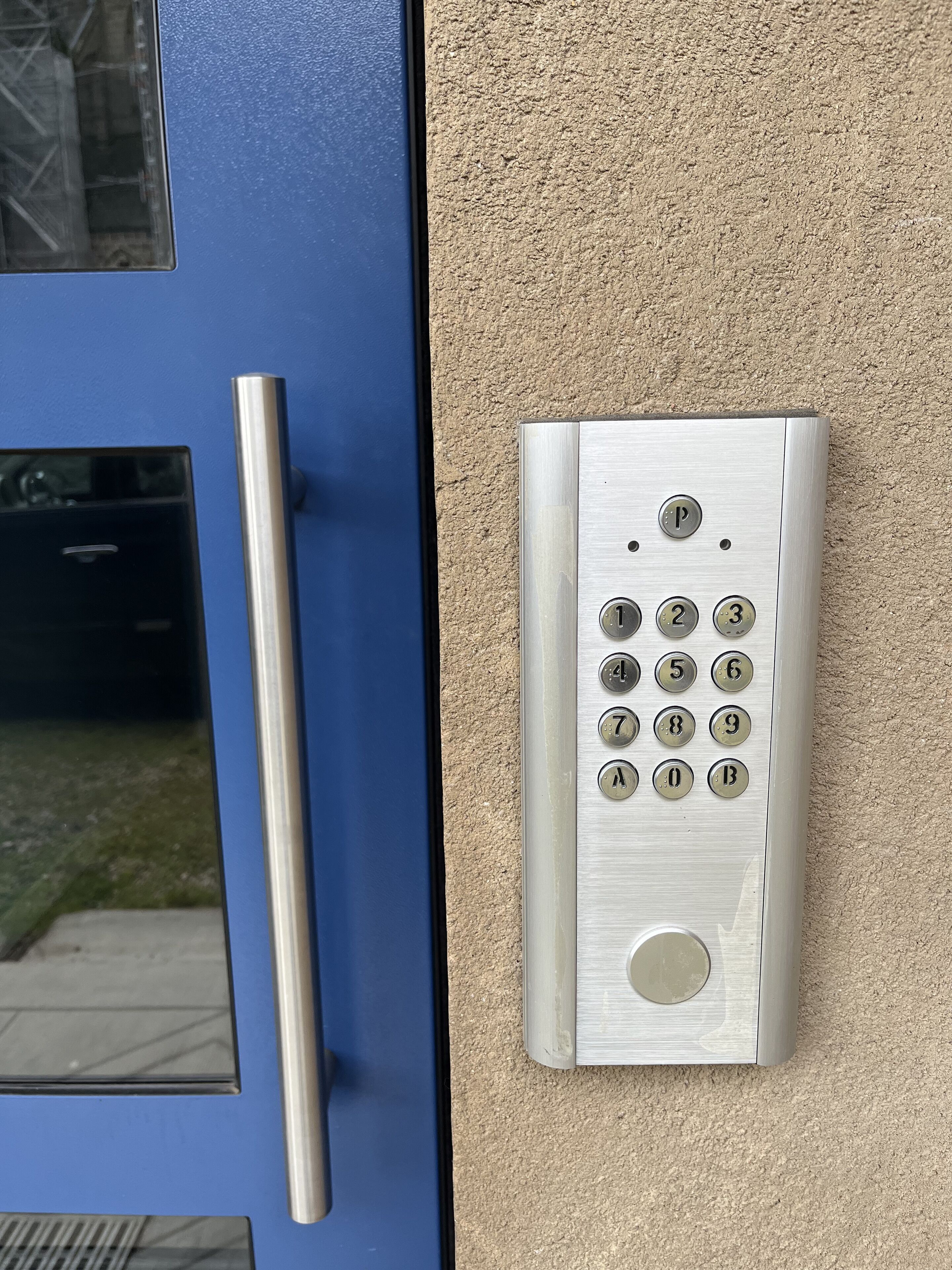 Una puerta azul con cerradura electrónica y un picaporte vertical.