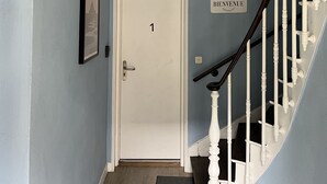 A hallway with a white door marked "1", a sign reading "REVENUE", and a staircase with white balusters. - Appartement rez -de Chaussée en Centre Ville (Dol-de-Bretagne)