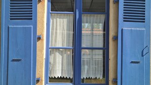A window with blue shutters and a lace curtain. - Appartement rez -de Chaussée en Centre Ville (Dol-de-Bretagne)