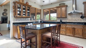 A spacious kitchen with a central island, wooden cabinets, and a large window providing natural light.
