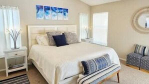A bedroom with a large bed, bedside tables, a nightstand, a window with curtains, and a wall-mounted mirror. - The Art House @ Walt Disney (Davenport)