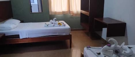 Habitación de hotel con dos camas individuales, televisión, espejo y ventana con cortinas.