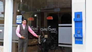 A hotel entrance with a sign reading "CAMU CAMU HOTEL" and a Visa sign indicating payment acceptance.