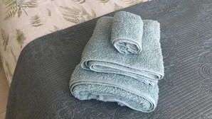 Un lit recouvert d’une couvre-lit à motifs, deux oreillers ornés de motifs d’ananas et une serviette pliée posée sur le lit.
