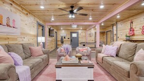 A cozy log cabin interior with two sofas, a coffee table, and a ceiling fan. - Pink Pines by Avantstay Luxury Aesthetic Dream Home, Indoor Pool, Hot Tub (Sevierville)