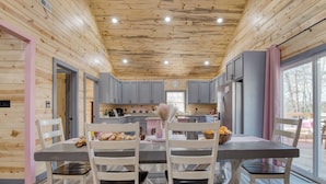A modern kitchen with wooden walls, grey cabinets, and a central island with seating. - Pink Pines by Avantstay Luxury Aesthetic Dream Home, Indoor Pool, Hot Tub (Sevierville)