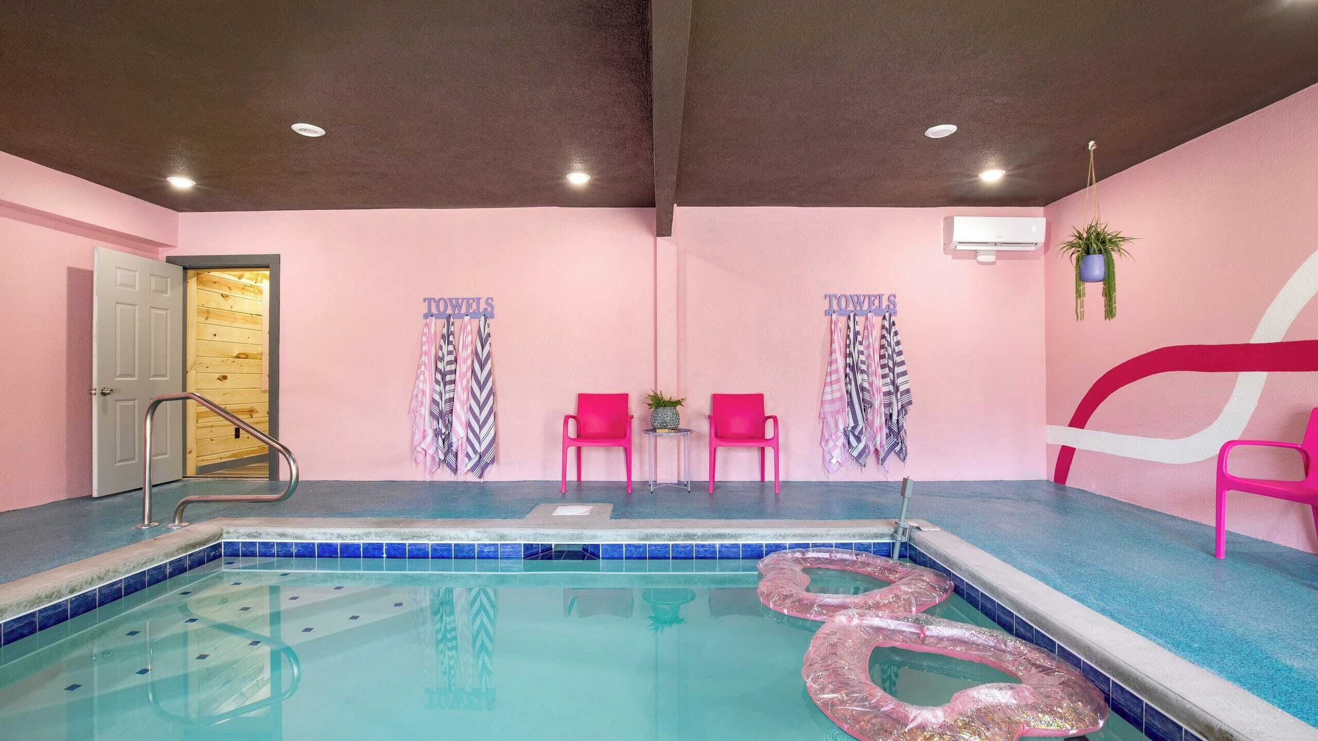Ein Hallenbad mit rosa Stühlen und Handtüchern an den Wänden.