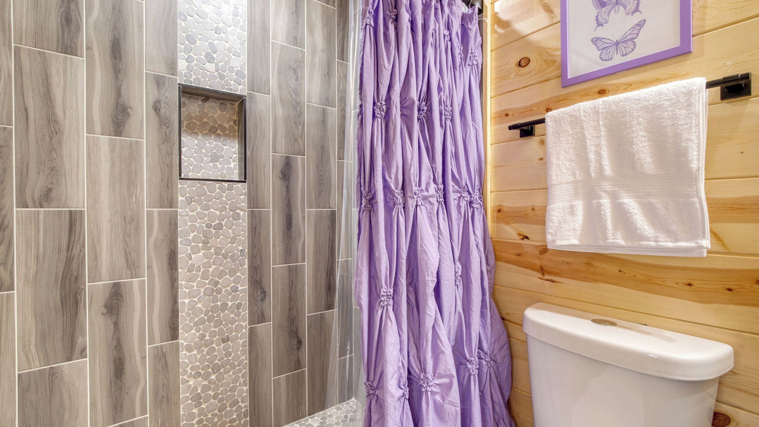 A bathroom with a shower, a toilet, and a towel rack.