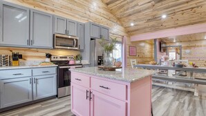 A modern kitchen with grey and pink cabinetry, stainless steel appliances, and a central island. - Pink Pines by Avantstay Luxury Aesthetic Dream Home, Indoor Pool, Hot Tub (Sevierville)
