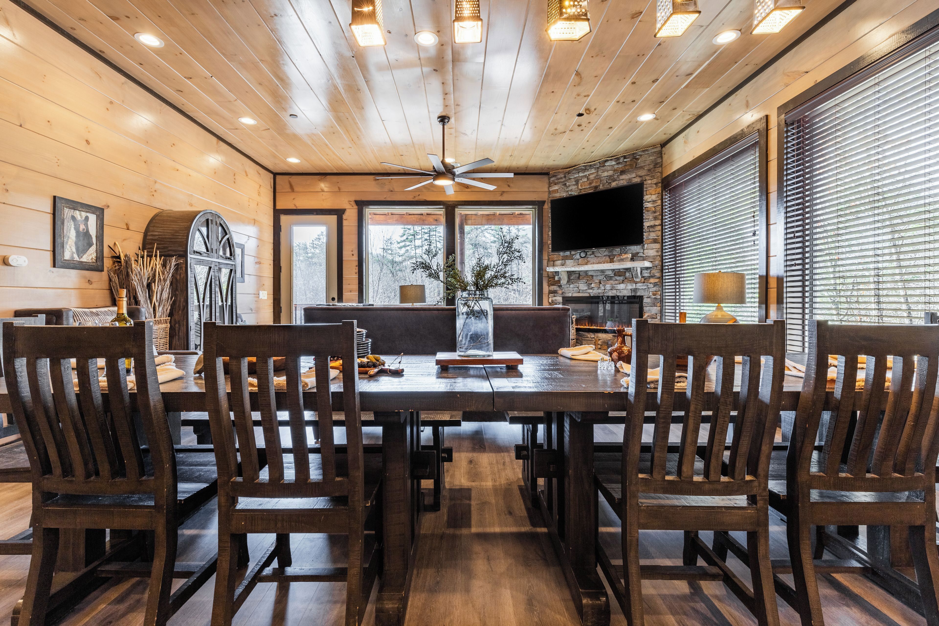 Un intérieur en bois comprenant une table à manger, des chaises, un ventilateur de plafond et une cheminée en pierre.