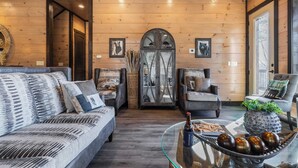A cozy living room with a sofa, armchairs, a glass coffee table, and a decorative door. - Sleeps 18 Luxury Lodge w/ Indoor Pool, Theater, Hot Tub, Game Room Elk Pass (Sevierville)