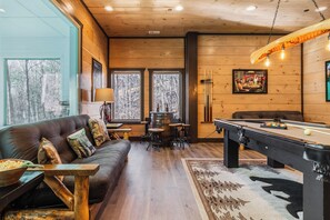Una habitación acogedora con mesa de billar, sofá y zona de bar.