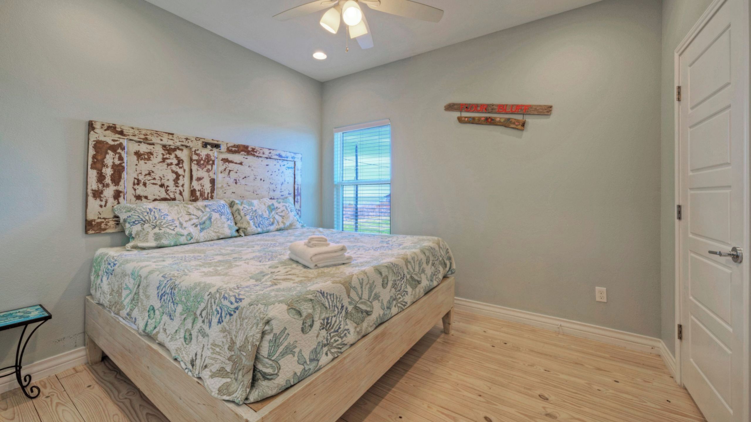 A bedroom with a bed, a ceiling fan, a window, and a door.