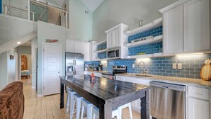 Una cocina moderna con armarios blancos, encimera negra y azulejos azules en la pared de atrás.