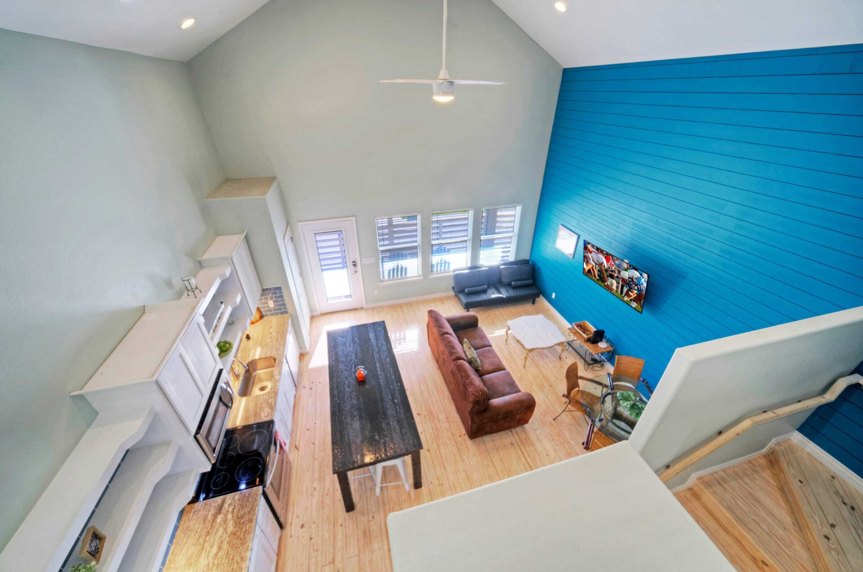 A spacious living area with a high ceiling, a dark wooden coffee table, a red sofa, and a blue accent wall.