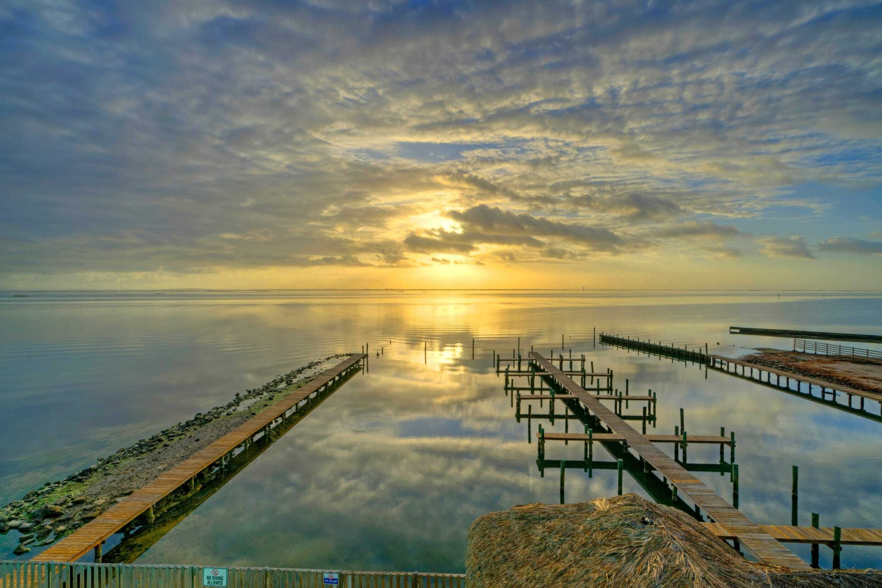 A calm lake with a wooden pier extending into the water, surrounded by a rocky shoreline.