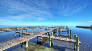 A wooden pier extending into calm water with clear skies. - Bay Haven w/ Shared Boat Dock & Waterfront Pool Big Trout by Avantstay (Corpus Christi)