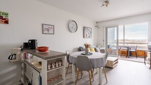 Une cuisine moderne avec un coin repas, comprenant une machine à café, un panier et une horloge murale.