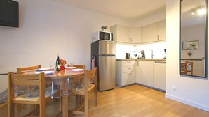 Una cocina compacta con una mesa de comedor, sillas, un refrigerador, un microondas y un lavamanos.
