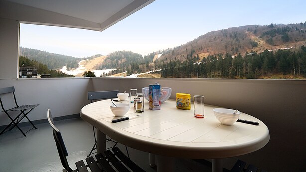 Un balcón con una mesa, sillas y vistas a un valle.