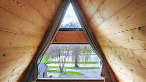 Una ventana de madera triangular con vistas a un parque y un edificio.