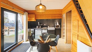 Una cocina moderna con paredes de madera, una mesa de comedor de vidrio y sillas negras.