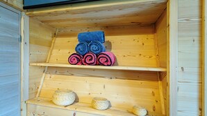 Un armario de madera con estantes que contienen toallas enrolladas y cestas tejidas.