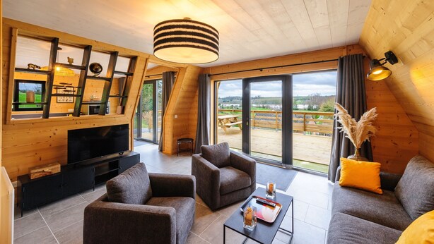 Una sala de estar moderna con un televisor grande, asientos cómodos y vistas al exterior.
