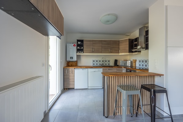 Eine moderne Küche mit Holzschränken, einer zentralen Kochinsel und einem integrierten Geschirrspüler.