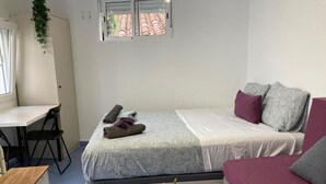 Una habitación pequeña con cama, escritorio y una mesita.