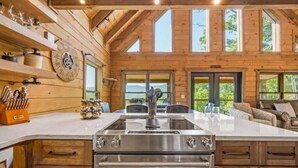 Une cuisine spacieuse dotée d’un grand îlot central, de murs en bois et offrant une vue sur l’extérieur.