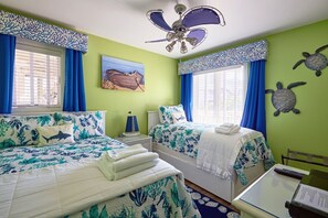 A room with two beds, a ceiling fan, a painting, and a turtle decoration on the wall.