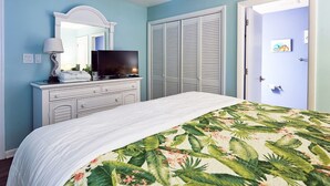 A bedroom with a bed, a dresser, a television, and a door.