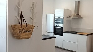 Una cocina moderna con armarios blancos, una cesta colgante con texto y un horno empotrado.