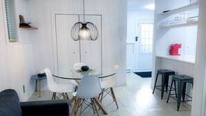 A modern dining area with a glass table, white chairs, and a unique pendant light.