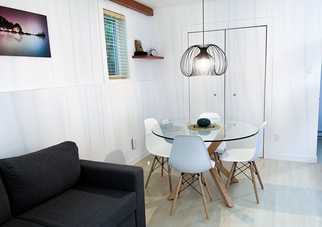 A modern dining area with a glass table, white chairs, and a unique pendant light.