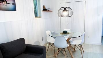A modern dining area with a glass table, white chairs, and a unique pendant light.