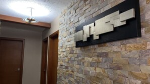 Um corredor com parede de pedra, porta de madeira e luminária no teto.